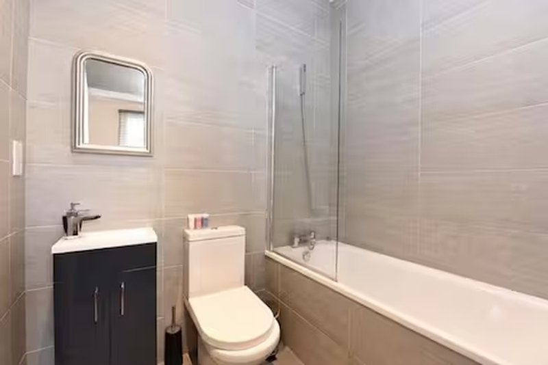 Modern bathroom with black vanity, toilet, bathtub, shower screen and mirror