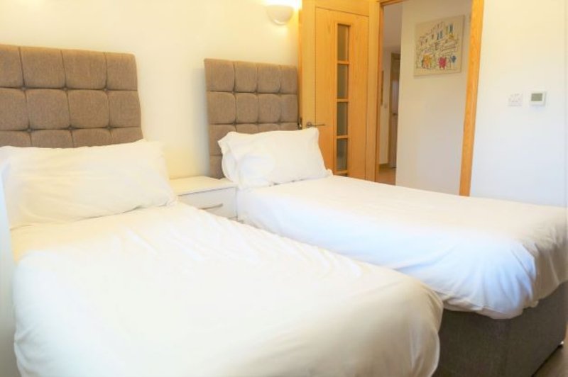 Twin bedroom with two single beds, padded headboards, wooden doors and wardrobe