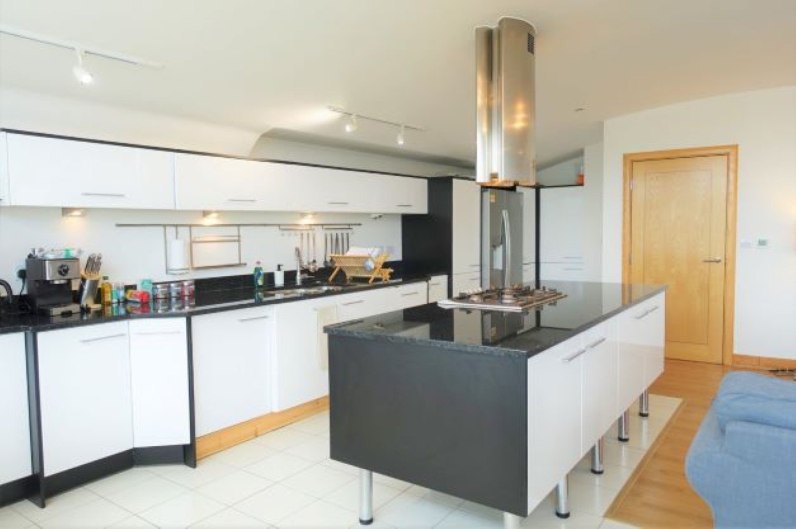 Modern kitchen with white cabinetry, black island, stainless steel appliances and wooden door