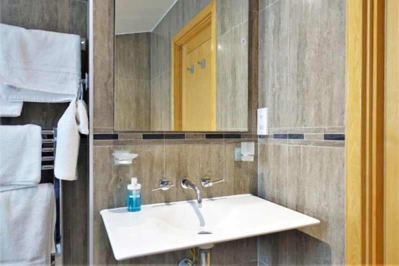 Modern bathroom with white sink, mirror, towel rail and wood-grain tile walls