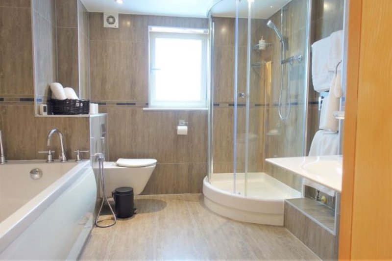 Modern bathroom with bathtub, corner shower enclosure, dual vanity sink and window