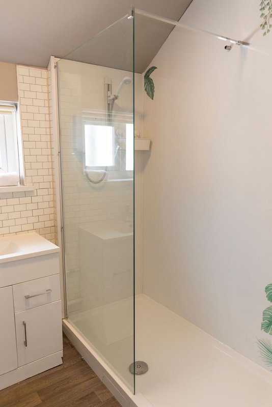Modern bathroom with walk-in shower, glass enclosure, subway tile walls and vanity sink