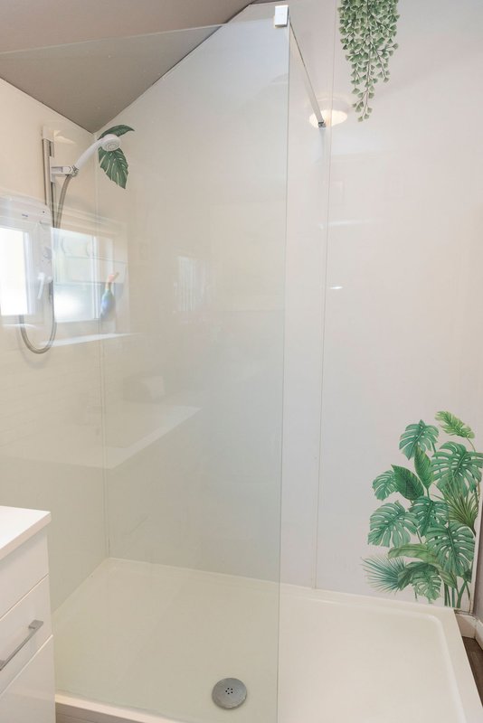 Modern bathroom with walk-in shower, glass enclosure, white tiles and potted plants