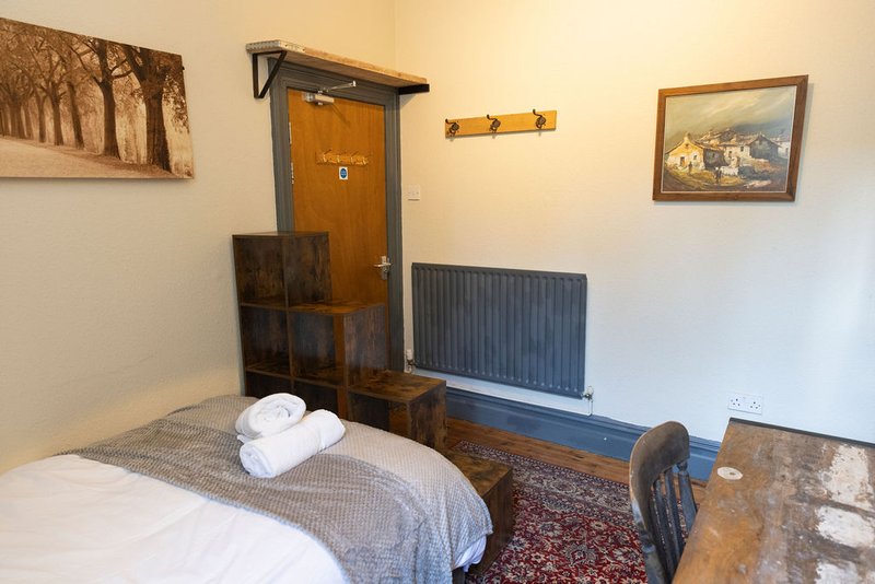 Bedroom with single bed, wooden wardrobe, radiator, framed wall art and towels