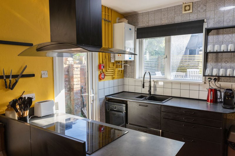 Modern kitchen with yellow accent wall, black cabinetry, stainless steel appliances and island counter