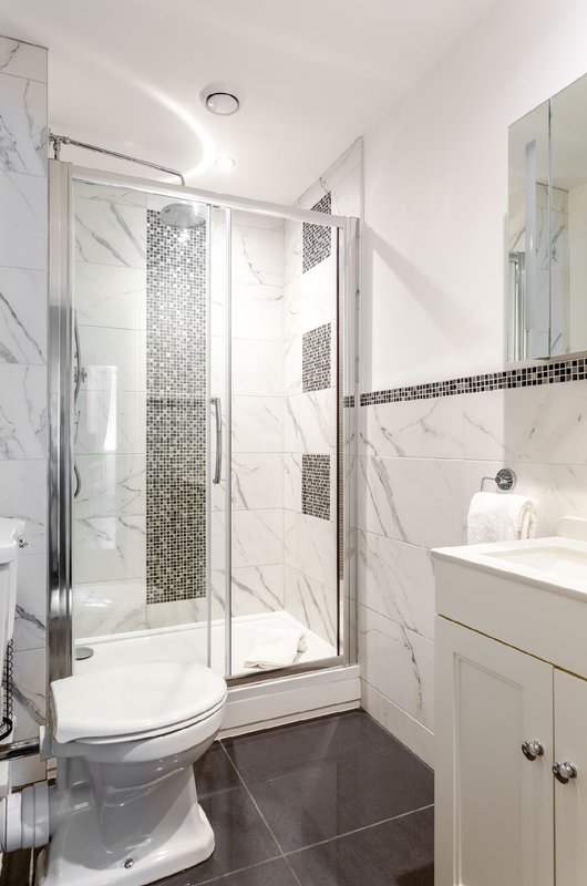 Modern bathroom with walk-in shower, white vanity, marble tiles and chrome fixtures