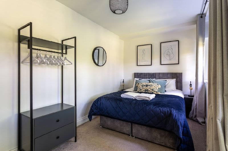 Bedroom with double bed, navy bedding, metal wardrobe, and wall art
