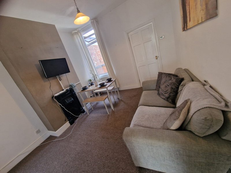 Living room with beige sofa, TV on stand, desk, window and pendant light