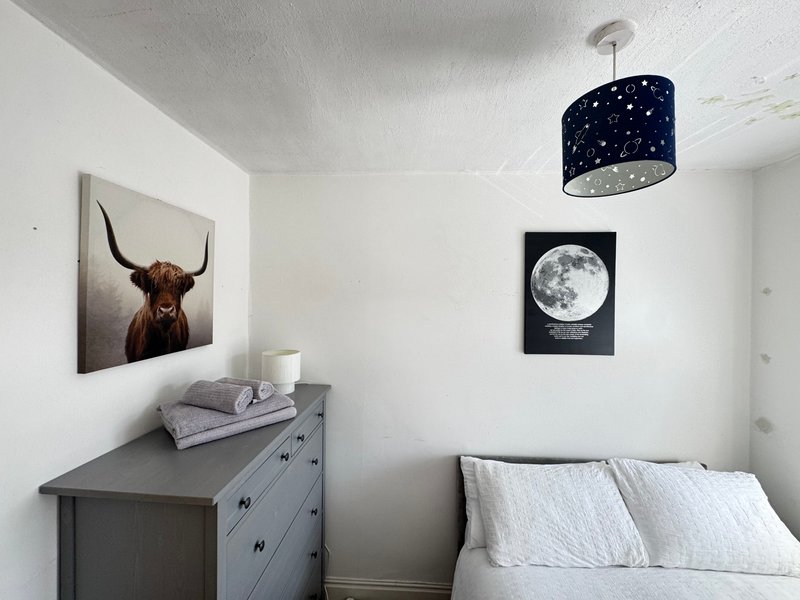 Bedroom with bed, grey dresser, framed artwork, and starry pendant light fixture