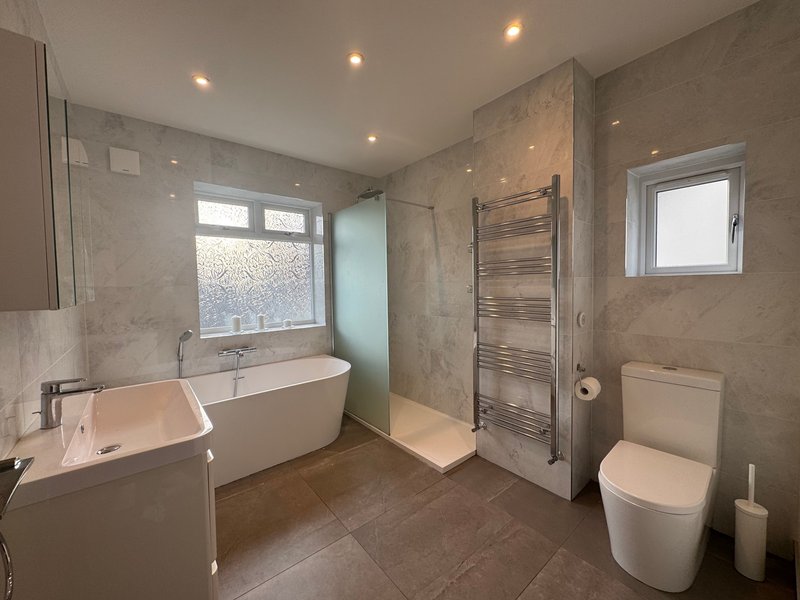 Modern bathroom with freestanding tub, walk-in shower, toilet, and dual sinks