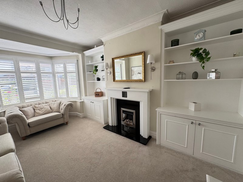 Bright living room with cream sofa, fireplace, built-in shelving and large bay window
