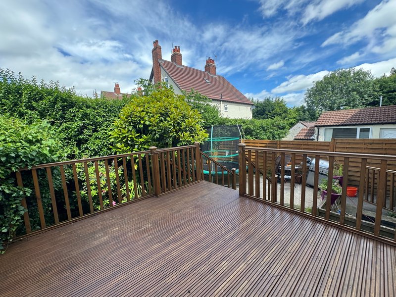 Wooden deck with railings overlooking gardens and countryside house views