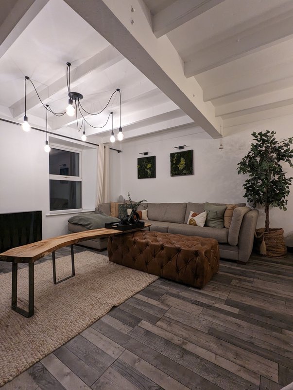 Modern living room with gray sofa, wooden coffee table, pendant lights, and potted plant