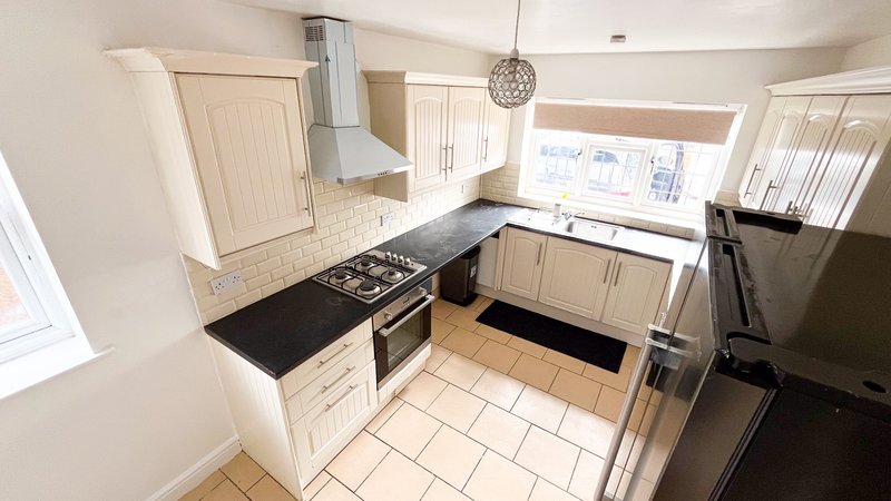 Modern kitchen with cream cabinets, black countertops, gas range and stainless steel appliances