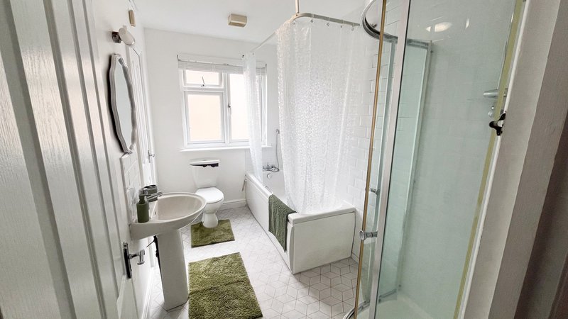 Modern bathroom with white tiles, shower enclosure, bathtub, sink and window