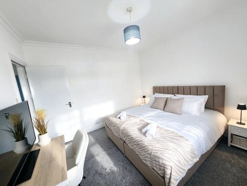 Modern bedroom with double bed, grey headboard, desk, mirror and pendant light