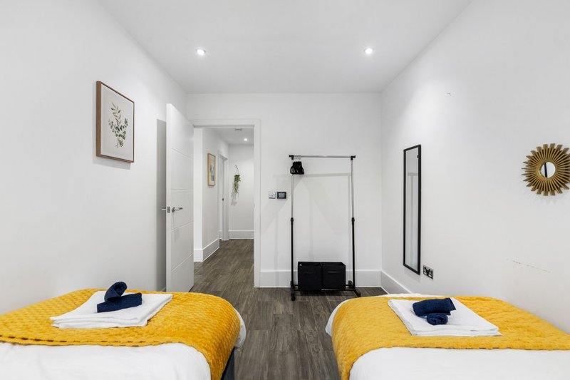 Twin bedroom with yellow bedding, ensuite bathroom, and modern minimalist décor