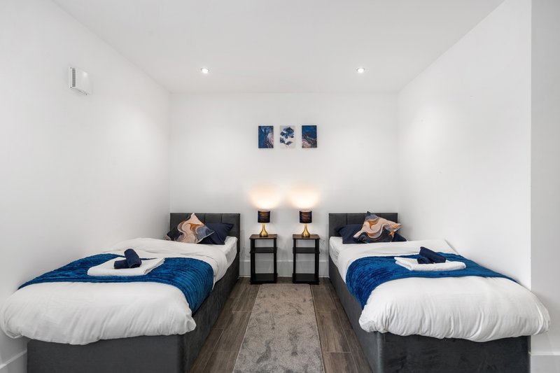 Twin bedroom with two beds, blue bedding, nightstands, and wall art