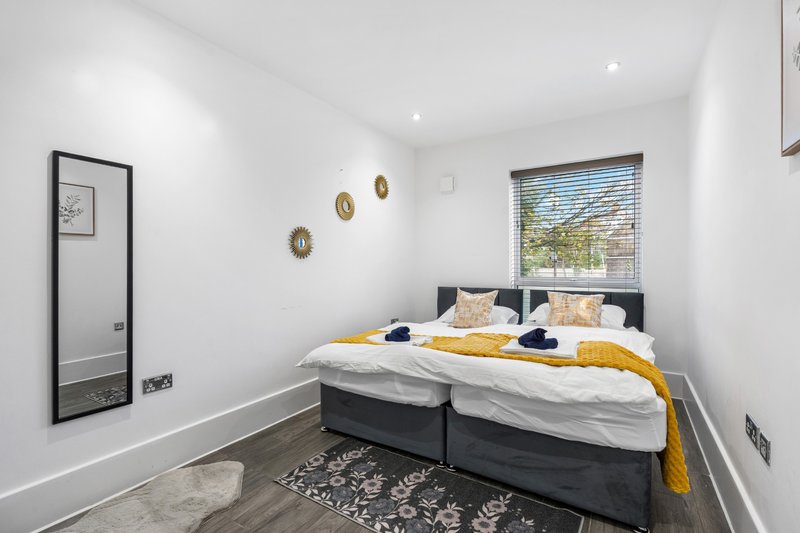 Modern bedroom with double bed, yellow throw, gold wall decor and large window