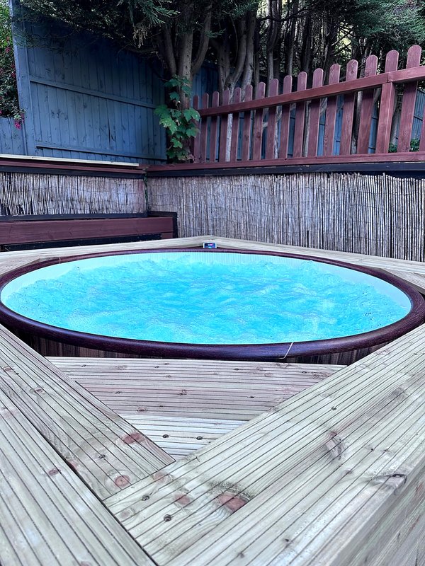 Backyard with round above-ground swimming pool, wooden deck and red fence