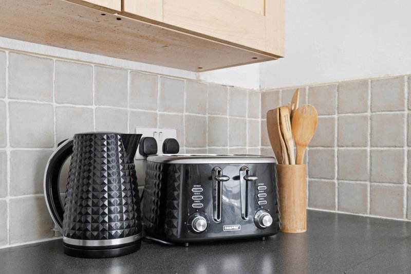 Kitchen countertop with kettle, toaster, utensil holder and white tile backsplash