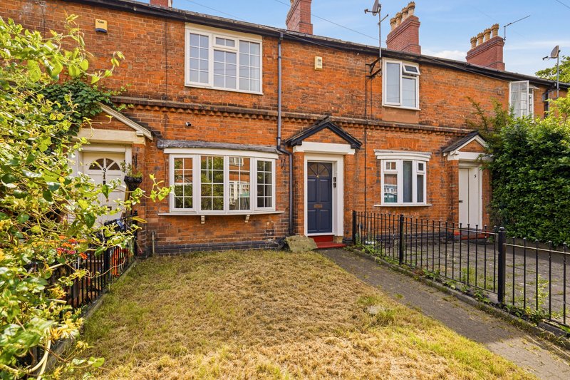 Red brick terraced house with front garden, driveway and black iron fence