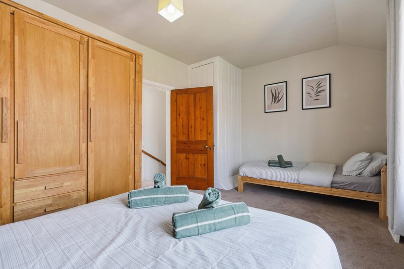 Bedroom with double bed, wooden wardrobe, single bed and framed wall art