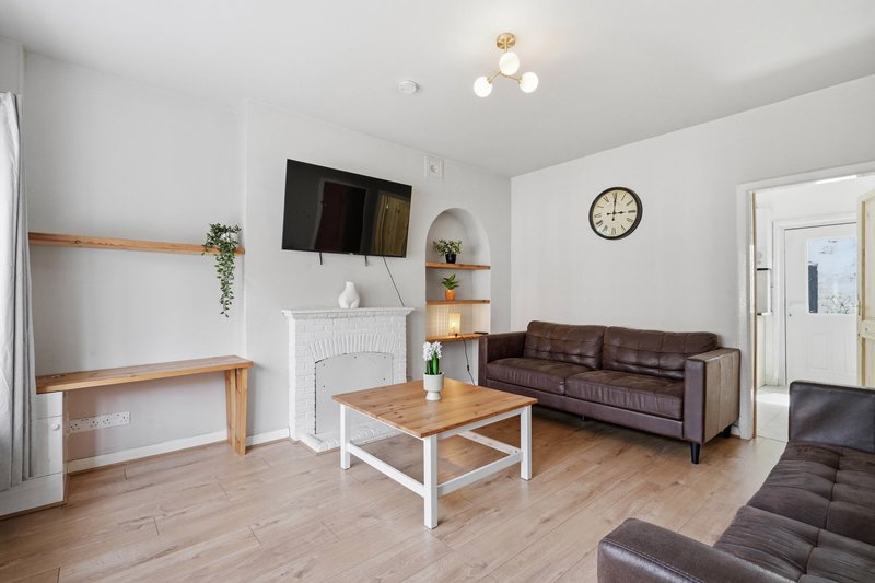 Modern living room with brown leather sofa, wooden coffee table, wall-mounted TV and fireplace
