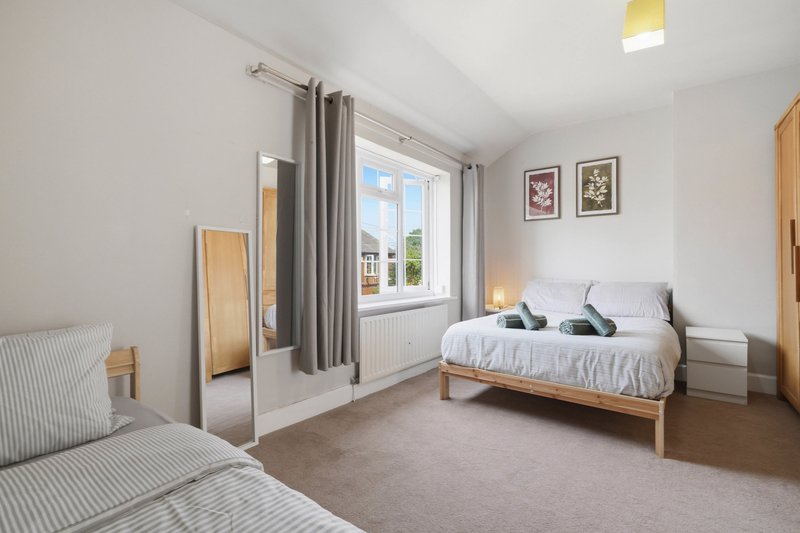 Bright bedroom with two beds, wooden furniture, large window with garden view