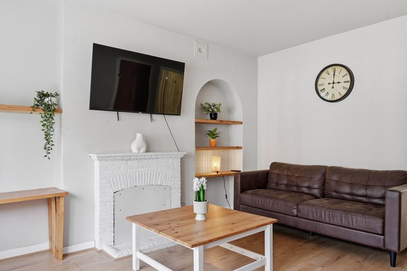 Modern living room with brown leather sofa, wooden coffee table, fireplace and wall-mounted television