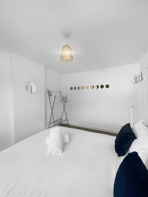 Minimalist bedroom with double bed, pendant light, decorative plates on wall, and dark throw blankets
