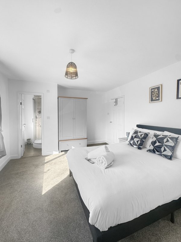 Bright modern bedroom with double bed, pendant light, wardrobe and ensuite door