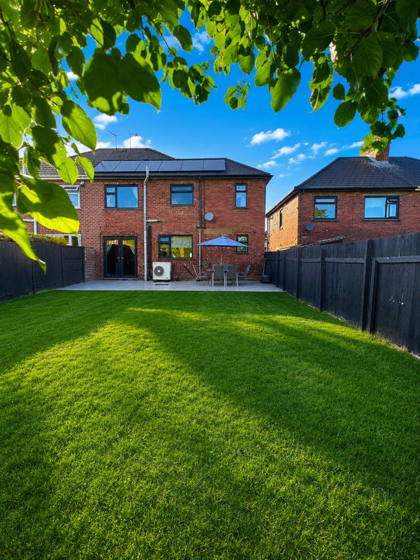 Modern brick house with garden, patio area, solar panels and manicured lawn