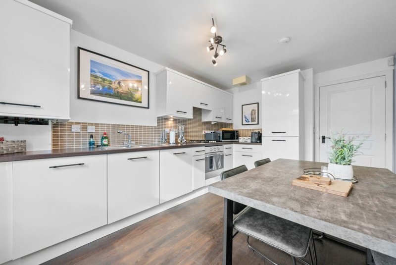 Modern white kitchen with island, stainless steel appliances and wooden flooring