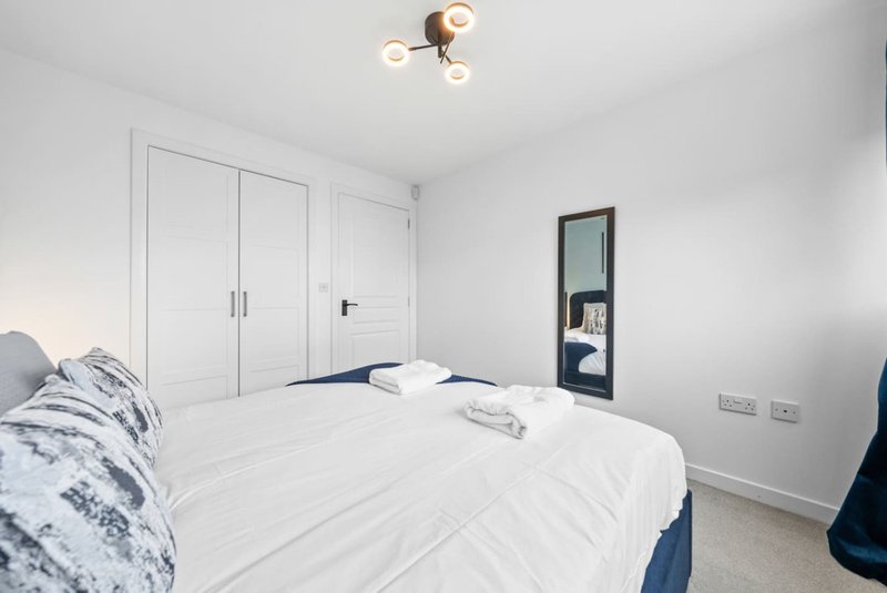 Modern bedroom with double bed, white wardrobes, ceiling light and mirror door