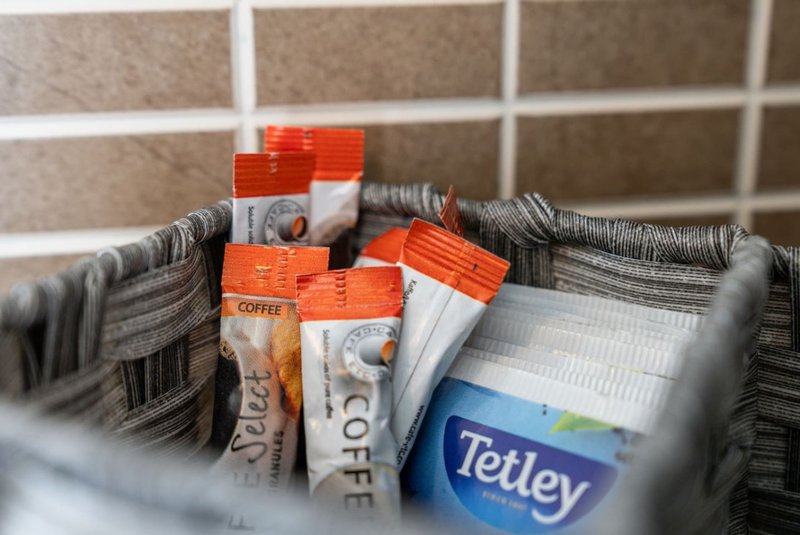 Bathroom shelf with towels, coffee sachets, and branded toiletries