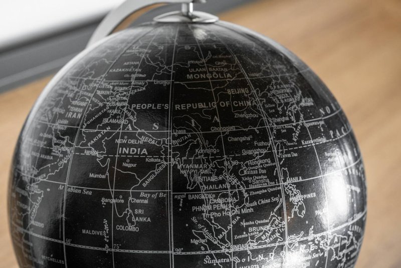 Close-up of decorative black and white globe with geographical markings and stand