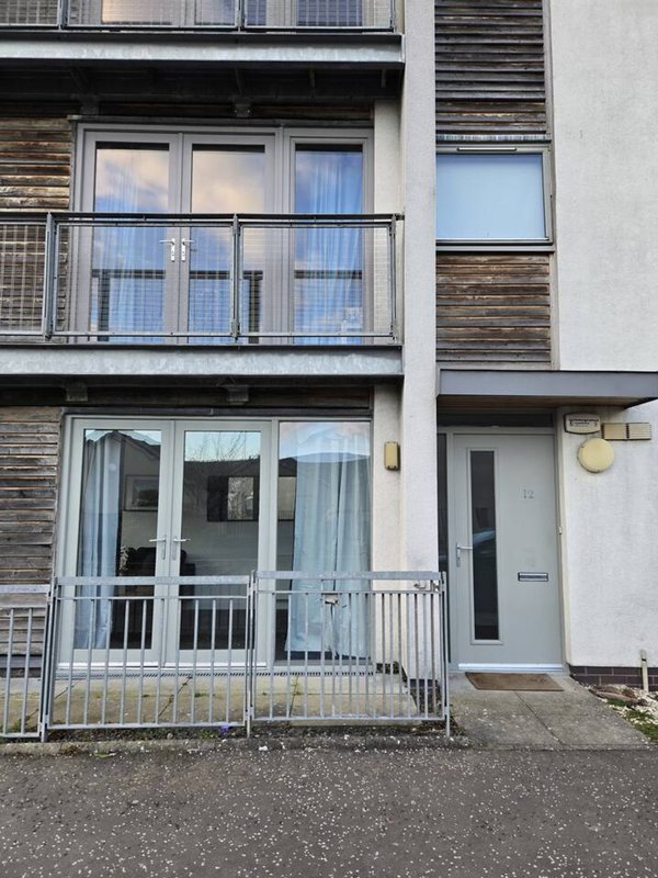 Modern apartment building exterior with balconies, ground-floor entrance and metal railings