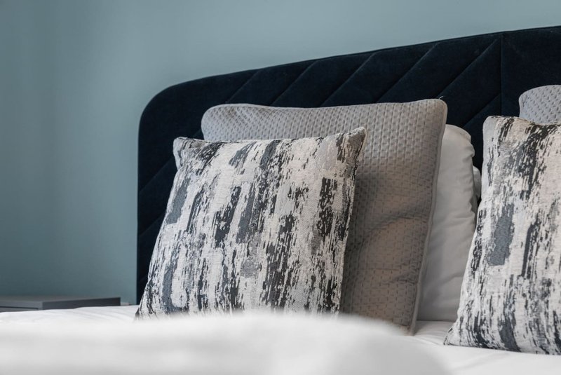 Bedroom detail with black upholstered headboard and patterned decorative pillows