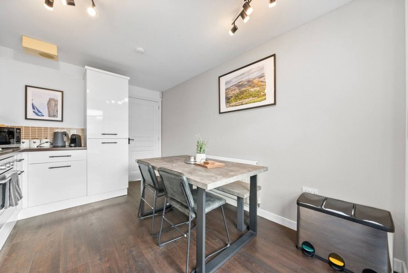 Modern kitchen-diner with white cabinetry, dining table, chairs and wooden flooring