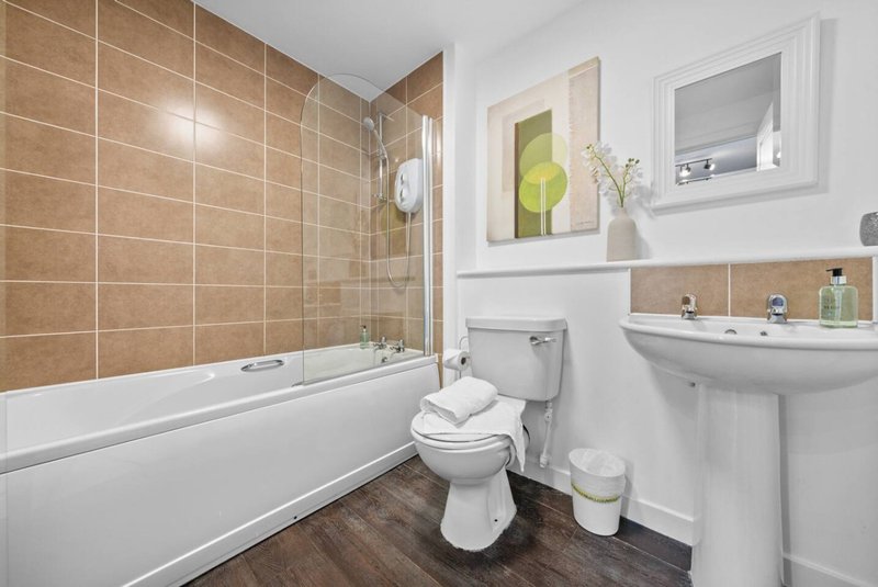 Bathroom with bathtub, toilet, pedestal sink, and decorative wall art