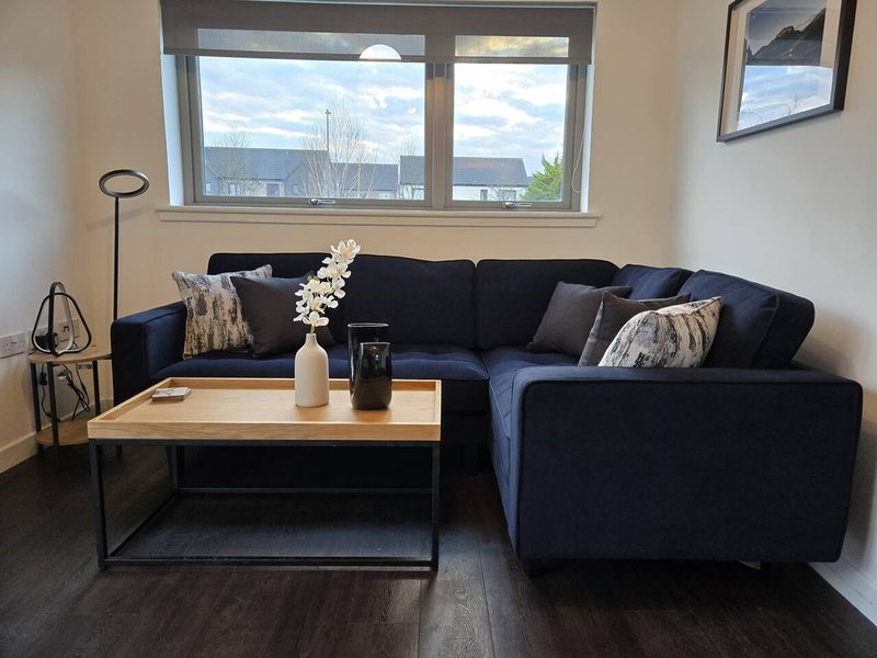 Modern living room with dark corner sofa, wooden coffee table, floor lamp and city views