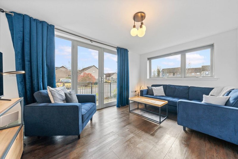 Bright living room with blue sofas, wooden floor, large windows and countryside views