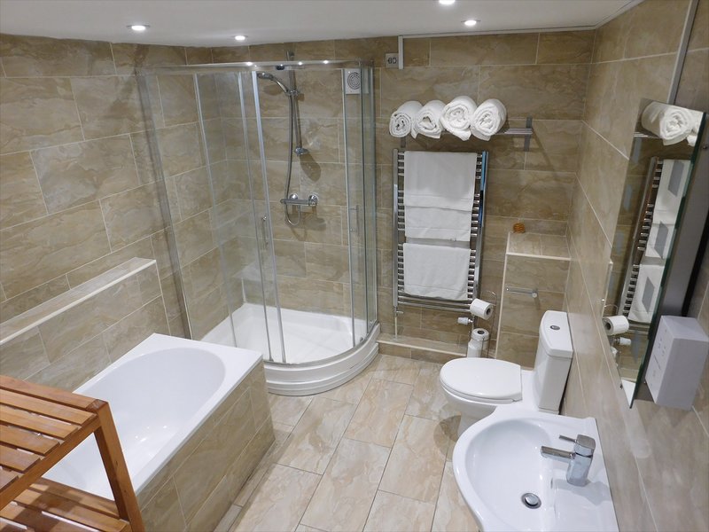 Modern bathroom with double sink, shower cubicle, bathtub and heated towel rail