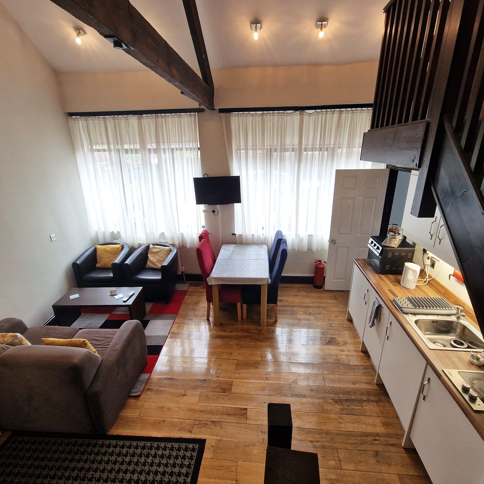 Open-plan studio apartment with kitchen, dining table, seating area and exposed beams