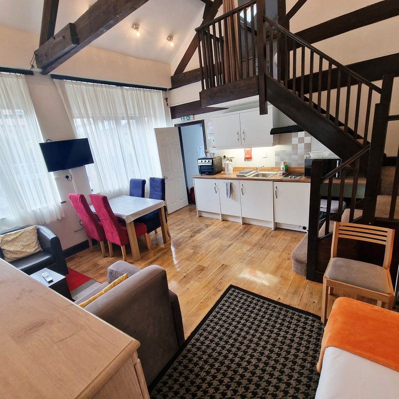 Open-plan living space with kitchen, dining area, staircase and contemporary furnishings