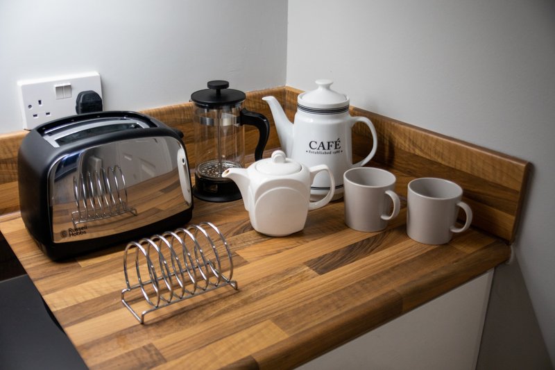 Kitchen counter with toaster, kettle, coffee pot, mugs and utensils