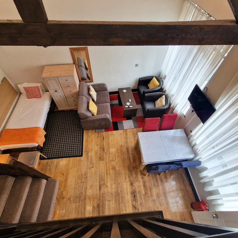 Overhead view of open-plan living space with wooden beams, furniture, and natural light from windows