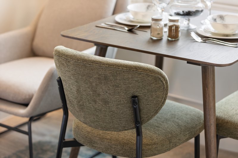 Modern dining area with upholstered chairs, wooden table, and place settings