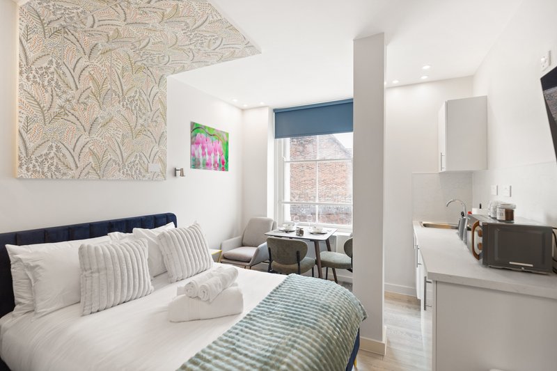 Modern bedroom with double bed, striped bedding, wall art, and en-suite bathroom visible